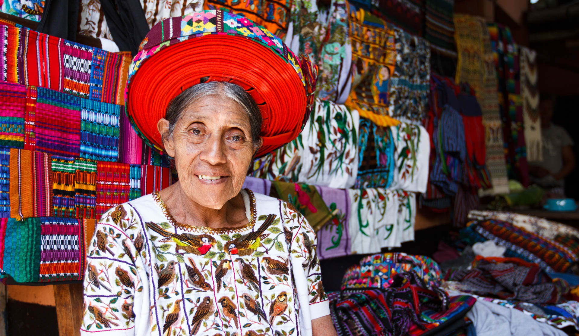 A woman surrounded by colourful woven textiles